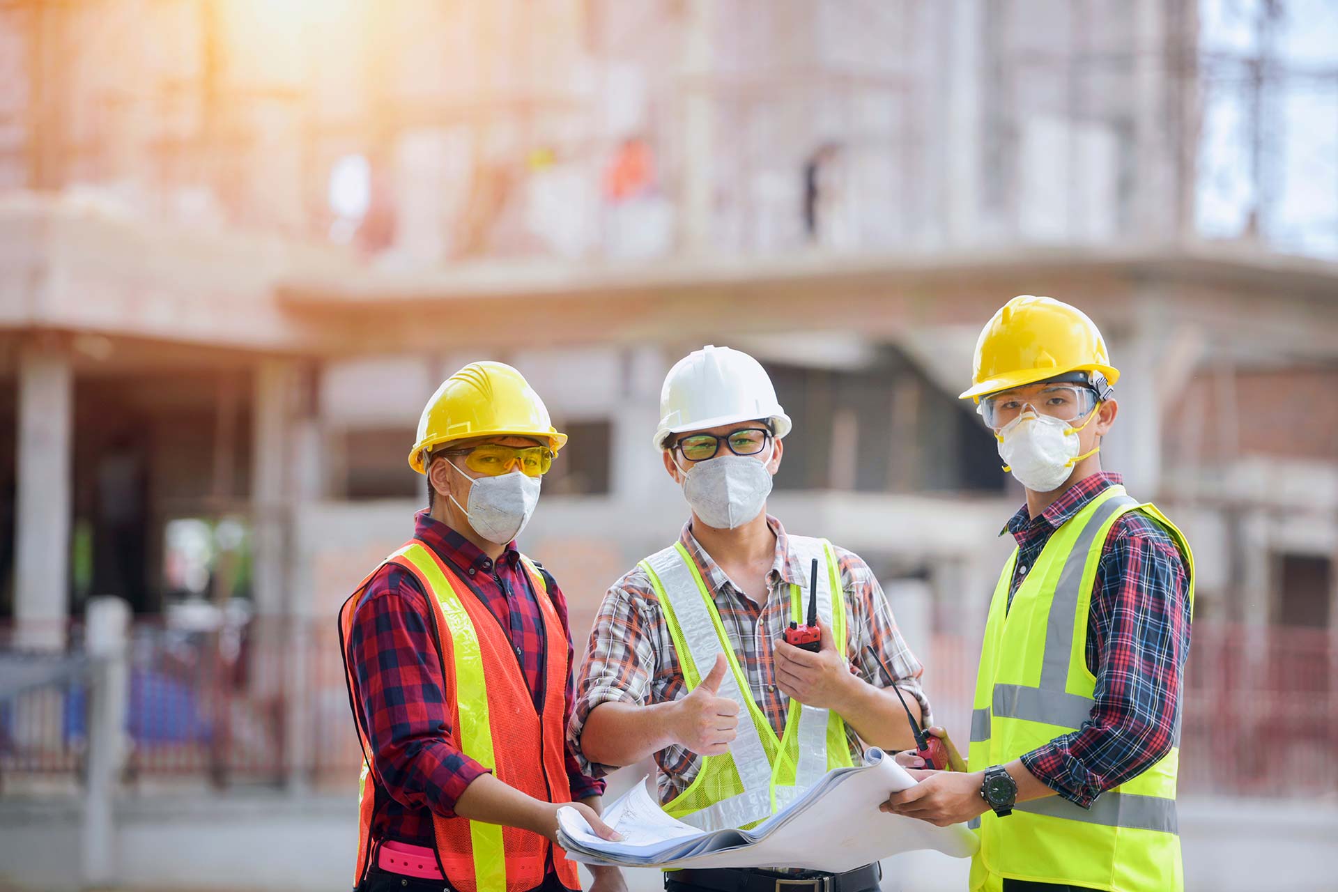3 construction workers holding a blueprint.