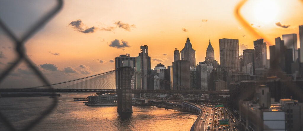 skyline view of New York City with bridge at sunset