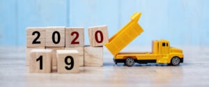 Toy dump truck adding a wooden block with 0 on it to a stack of wooden blocks to spell out 2020