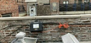 A roof of a historic building with vibration monitoring equipment installed on the wall.
