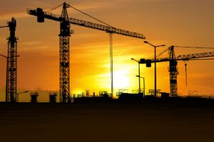 A sunset over three large cranes on an active construction site utilizing Saltus’ construction monitoring services.