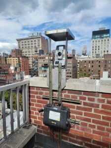 Automated optical structure survey system on a rooftop of a building during the daytime.