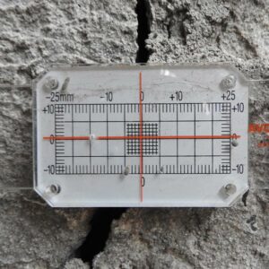 A close-up of an existing crack in a surrounding property being measured.