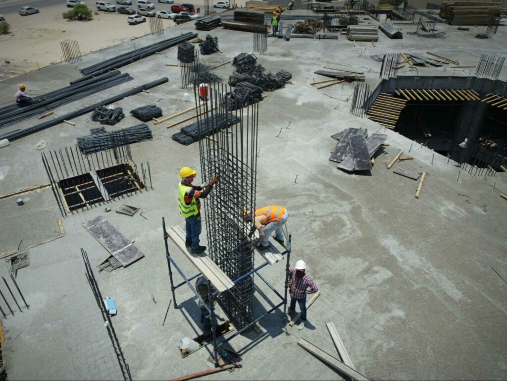 A group of workers standing on top of the foundation for a construction site.