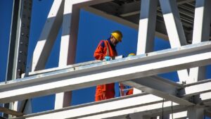 Two workers at an active construction site wearing helmets and protective gear.